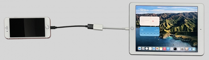 Photo of an iPhone connected to iPad with installed ra1npoc jailbreak.